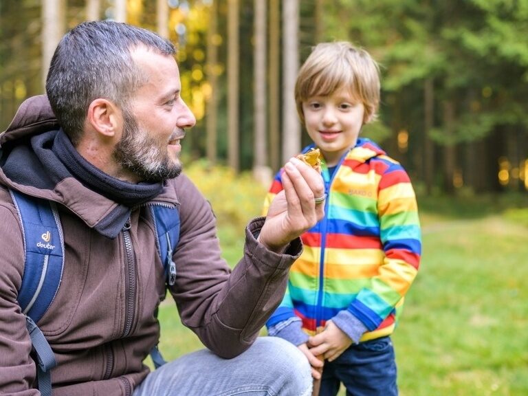 Ein Vater zeigt seinem Sohn einen Frosch auf seiner Hand. Ein schönes Naturerlebnis bei einer Familienwanderung durch den Thüringer Wald.