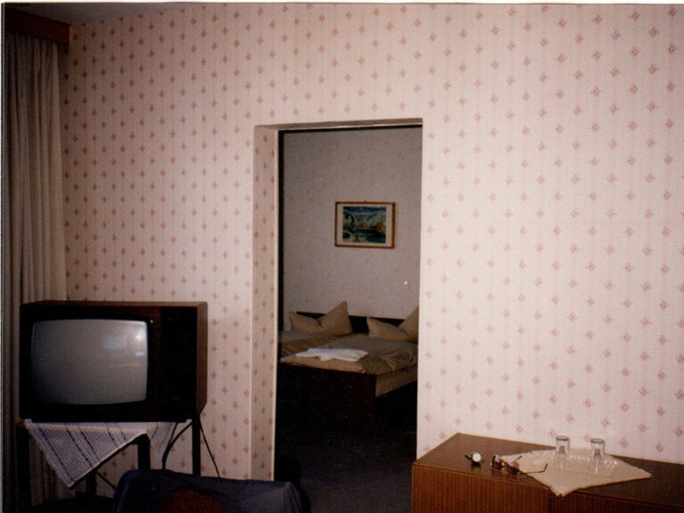 Altes 2-Raum-Hotelzimmer mit DDR-Tapete und Röhrenfernseher aus der Hotel-Chronik.