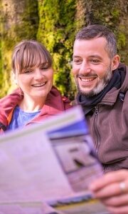Ein Paar schaut auf eine Wanderkarte, um die Umgebung während ihres Fastenurlaubs im Thüringer Wald zu erkunden.