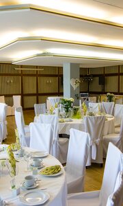 Restaurant, das für eine festliche Veranstaltung mit runden Tischen, Stuhlhussen und DJ-Equipment vorbereitet ist