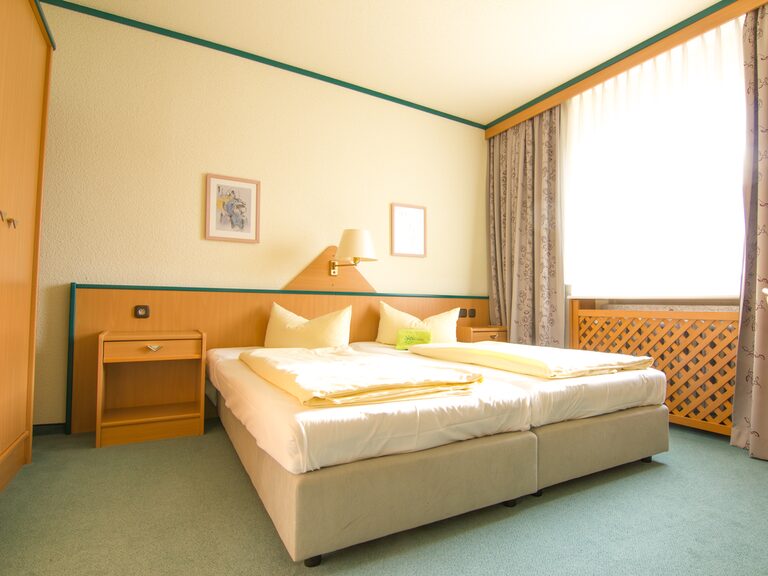 Das separate Elternschlafzimmer des Typ IV 2-Raum Familienzimmers mit Doppelbett und hellem Design. Ideal für entspannten Urlaub mit Kindern Thüringen.