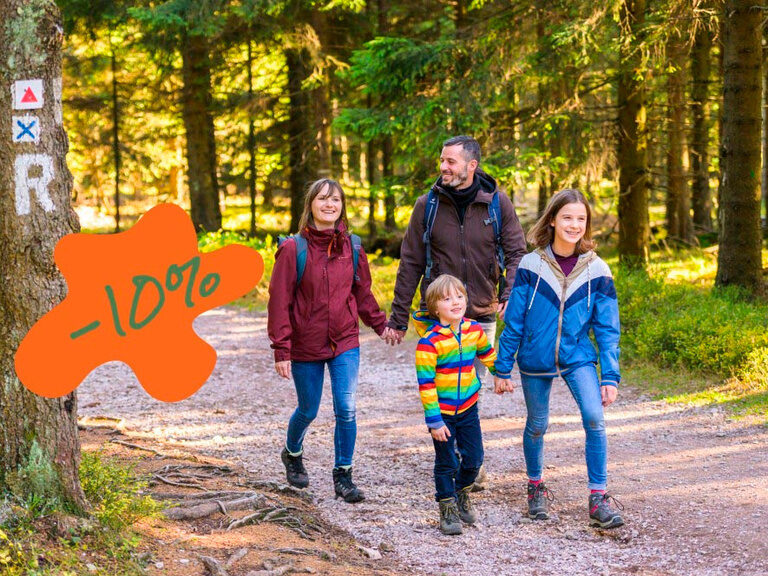 Eine Familie wandert durch den Wald auf dem Rennsteig, mit einem Prozentzeichen im Bild, das auf attraktive Angebote des Familienhotels hinweist.