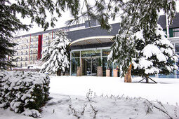 Der Haupteingang des Familienhotels mit der verschneiten Terrasse. Symbolisiert den Beginn eines gemütlichen Winterurlaubs im Thüringer Wald.