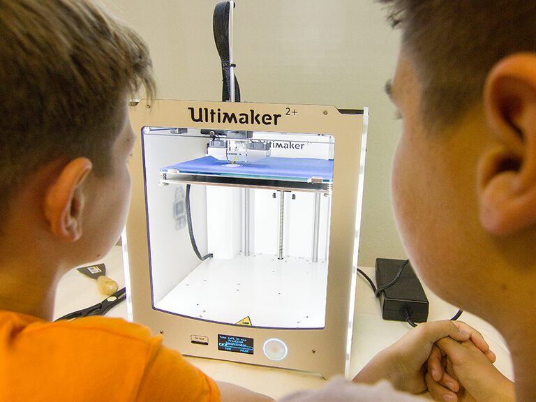 3D-Druck Familienhotel | Teenagerurlaub Thüringen Zwei Teenager sitzen konzentriert vor dem 3D-Drucker und verfolgen den Druck ihrer Kreation. Ein modernes Freizeitangebot für Jugendliche im Familienhotel Thüringen.